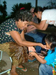 Little girl pouring water over mother's hands for Thai New Year