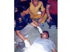 Bangkok corpse collectors kneel over body of young man on footbridge 